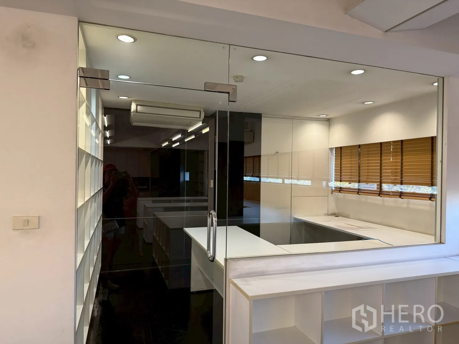 ออฟฟิศ for rent in Huai Khwang, Bangkok - มุมมองผ่านผนังกระจกไปยังโต๊ะทำงานและหน้าต่างติดมู่ลี่ ในสำนักงานแบบเปิด
