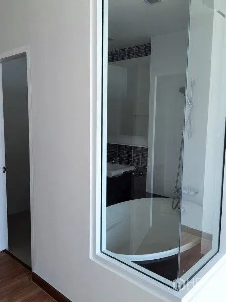 Condominium for sale in Bang Na, Bangkok - Glass-partitioned bathroom featuring a round soaking tub and handheld shower.