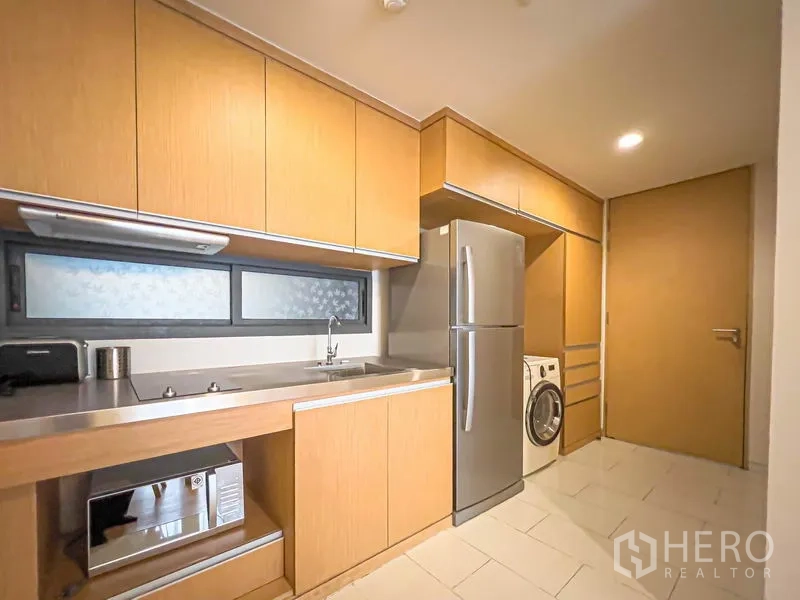 公寓 出售在Watthana, Bangkok - 一字型厨房，木质橱柜、不锈钢台面、水槽、微波炉、冰箱与洗衣机。