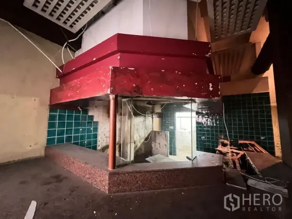 Shophouse for sale in Bang Rak, Bangkok - Old restaurant-style kitchen counter with a red hood and green tiled walls.