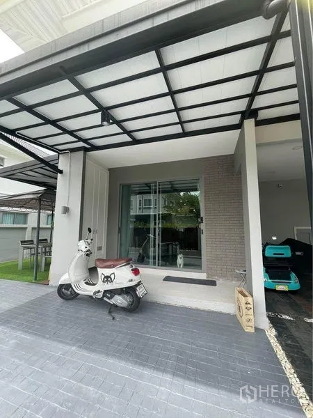 独立式住宅 出售在Lat Krabang, Bangkok - 住宅前方带顶车棚与门廊，推拉玻璃入户门。