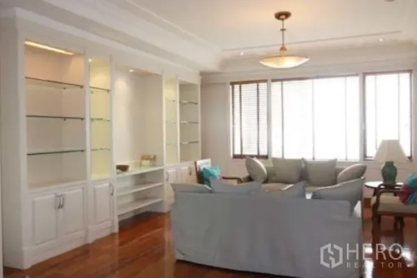 Condominium for rent in Sathon, Bangkok - Sunlit lounge with large windows, hardwood floors, pendant light and glass display cabinetry.