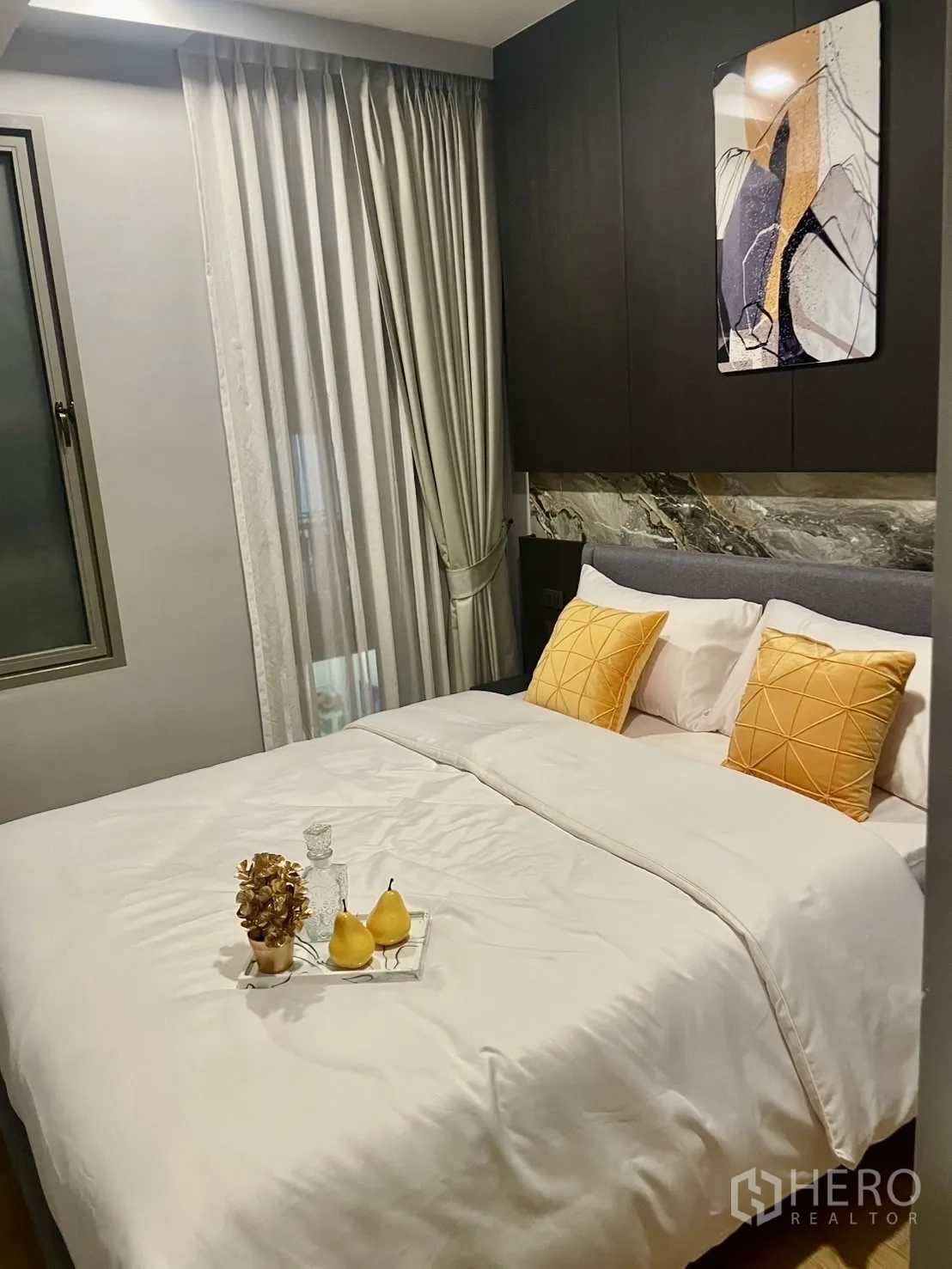公寓 出租在Watthana, Bangkok - 客卧以暖黄色为主调，墙面装饰画与层叠窗帘。
