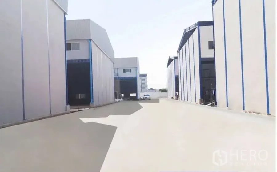 Warehouse for rent in Krathum Baen, Samut Sakhon - Wide concrete driveway between modern warehouse buildings with loading bays in Krathum Baen, Samut Sakhon.