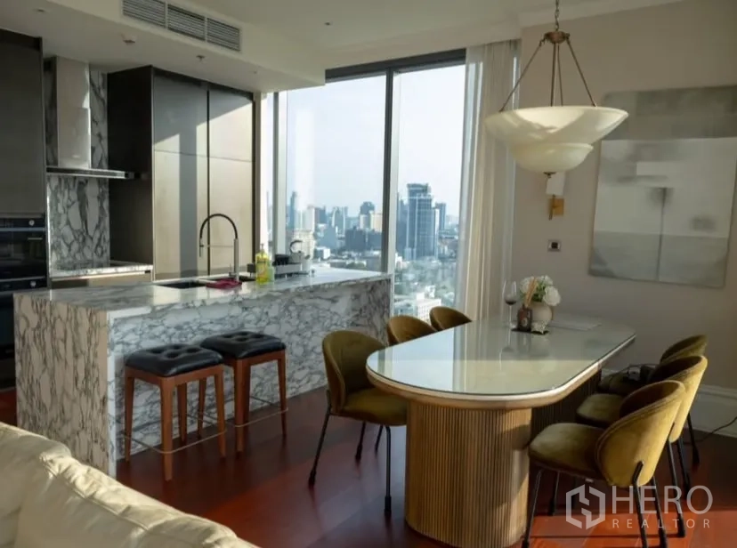 Condominium for rent or sale in Watthana, Bangkok - Marble kitchen island and dining area next to large windows.