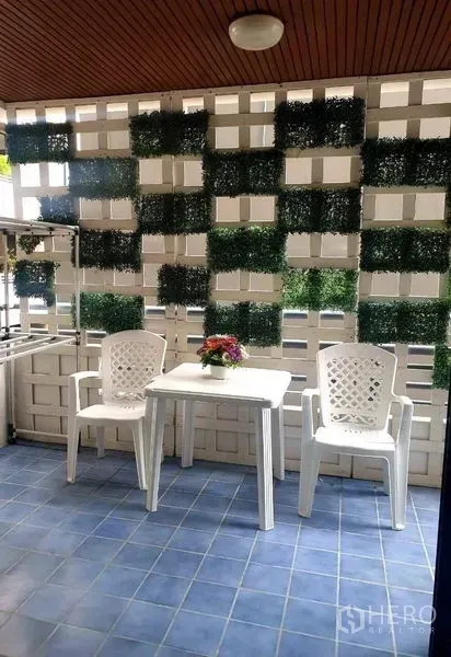 公寓 出租或出售在Watthana, Bangkok - 带顶阳台，蓝色地砖、白色桌椅与绿植装饰墙。