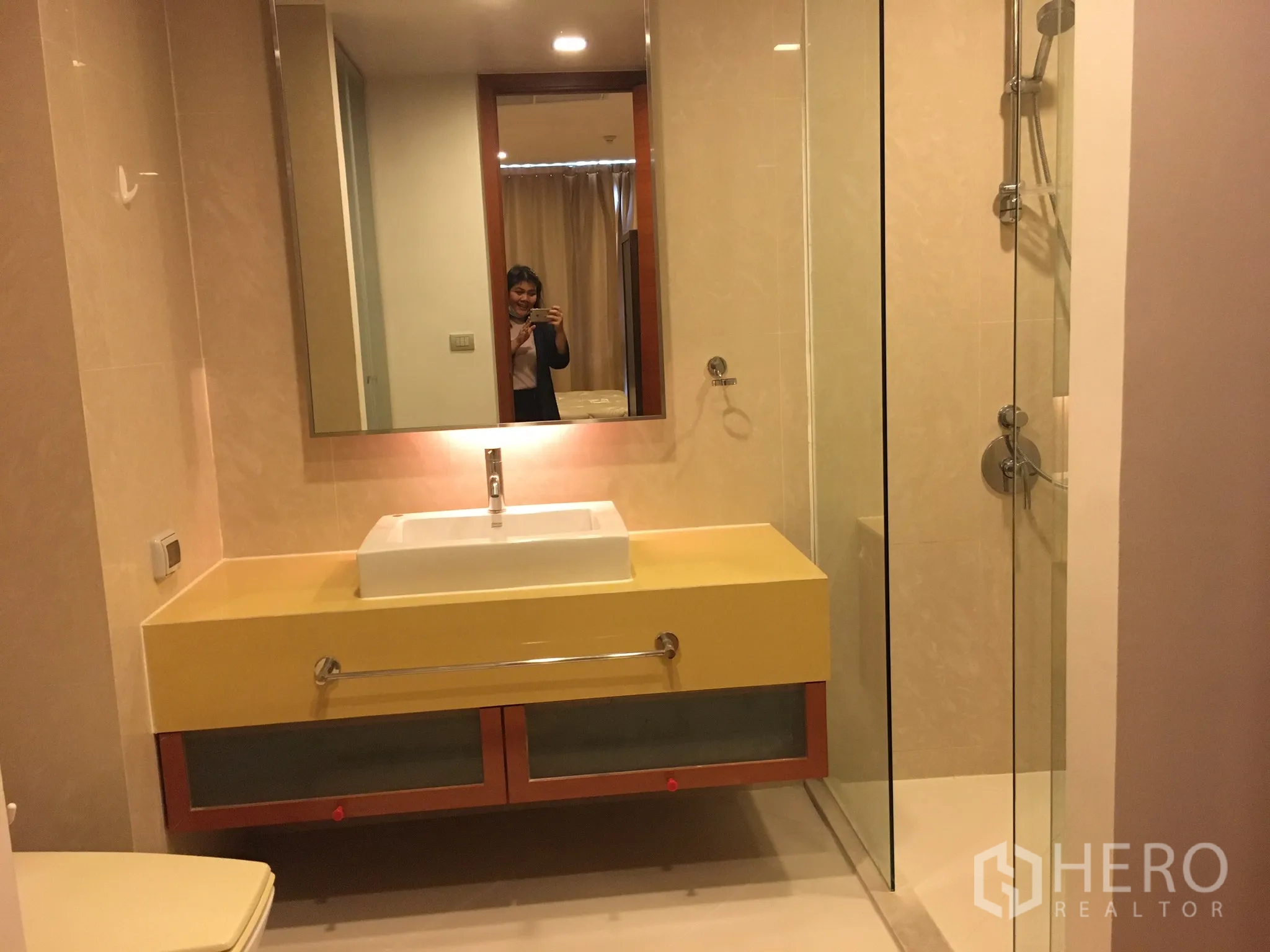 Condominium for rent in Khlong Toei, Bangkok - Bathroom featuring a glass-enclosed shower, wide mirror and vanity.