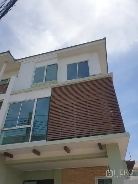 Townhouse for rent or sale in Yan Nawa, Bangkok - Modern three-storey townhouse facade with large windows and wood louver panels in Yan Nawa, Bangkok.