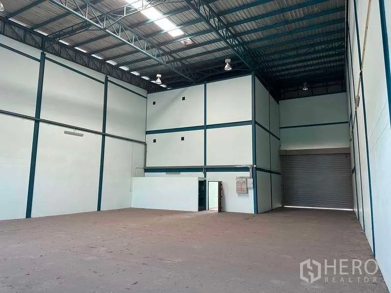 Warehouse for rent in Bang Phli, Samut Prakan - Spacious warehouse interior with skylights, steel beams and loading shutter.