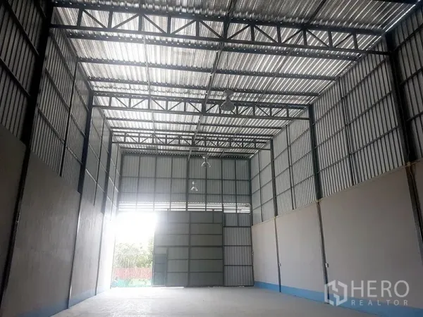 Warehouse for rent in Prawet, Bangkok - Wide, airy warehouse space with exposed steel trusses, skylight roof panels and industrial lights.