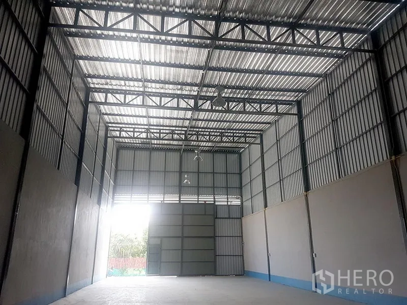 Warehouse for rent in Prawet, Bangkok - Wide, airy warehouse space with exposed steel trusses, skylight roof panels and industrial lights.