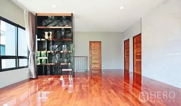 Detached House for rent in Bang Khae, Bangkok - Upstairs family area with glossy hardwood floors and a contemporary built-in shelving wall.