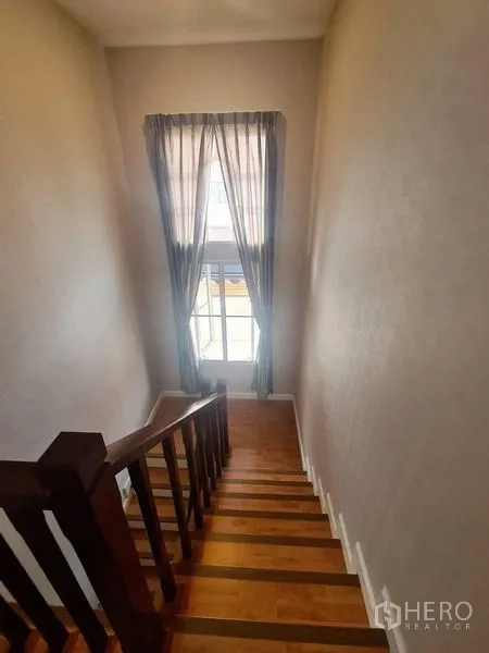 Detached House for rent in Sai Mai, Bangkok - Staircase with wooden steps and a tall window draped with sheer curtains.