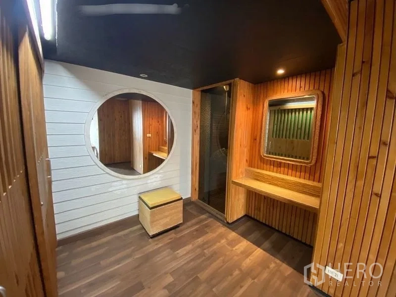 Condominium for rent or sale in Suan Luang, Bangkok - Dressing area with round feature mirror, built-in vanity, wood walls and glass shower entrance.