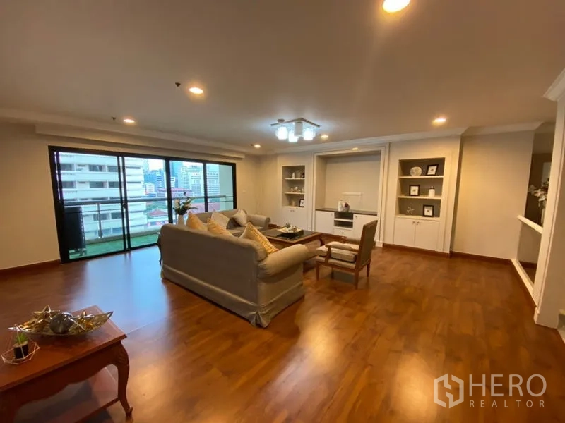 Condominium for rent in Watthana, Bangkok - Bright living area opening to a balcony with city views and built-in cabinetry.