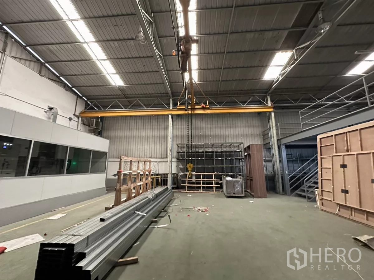 Warehouse for rent in Yan Nawa, Bangkok - Close-up of a traveling crane and hook beneath a lit steel roof.