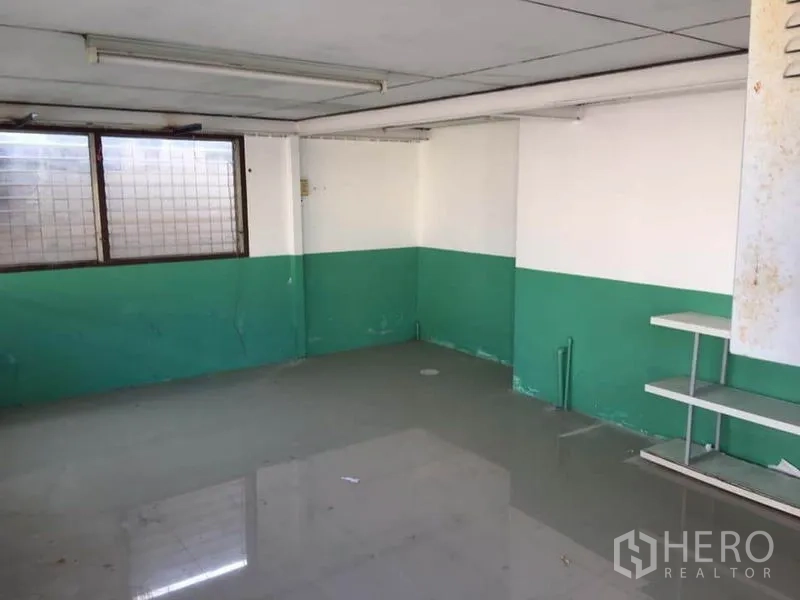 Warehouse for rent in Samut Prakan - Small office or storage room with tiled floor and green-and-white walls.