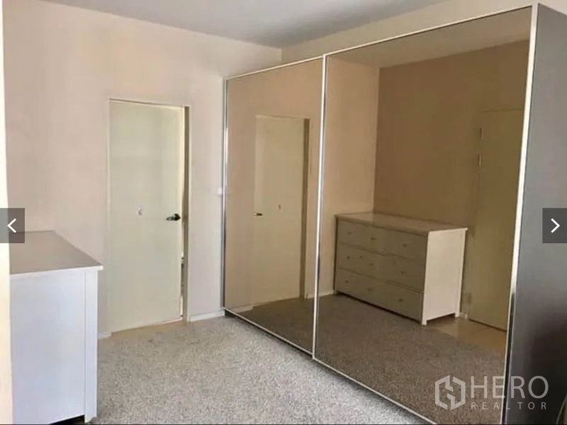 Townhouse for rent or sale in Suan Luang, Bangkok - Bedroom fitted with large mirrored wardrobes and a dresser providing ample storage.