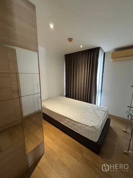 公寓 出租在Watthana, Bangkok - 温馨卧室，单人床、深色遮光窗帘与木地板。