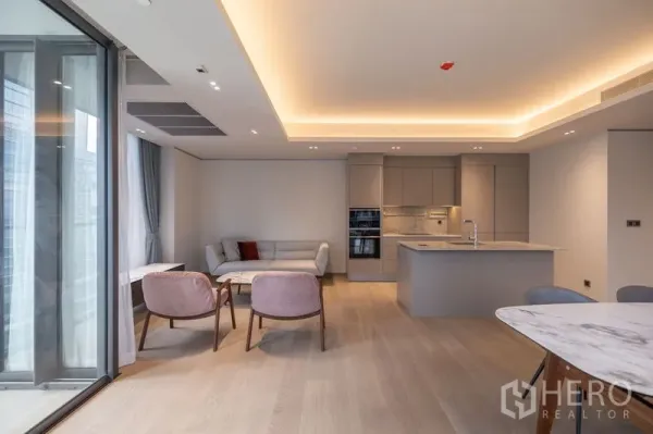 Condominium for rent in Pathum Wan, Bangkok - Cozy seating corner with sofa and armchairs next to full-height glass showcasing city views.