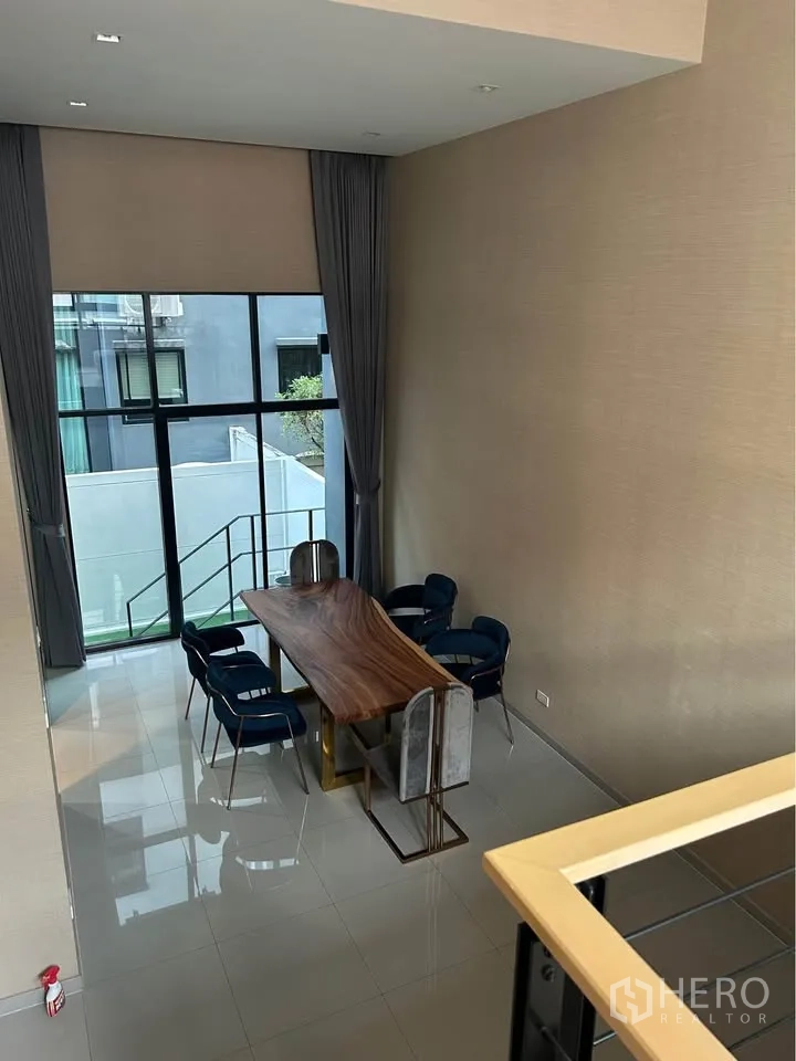 ทาวน์เฮาส์ for rent in Suan Luang, Bangkok - โถงรับประทานอาหารเพดานสูง โปร่งโล่ง ผนังกระจกเต็มบาน โต๊ะไม้ยาวพร้อมเก้าอี้สีน้ำเงิน