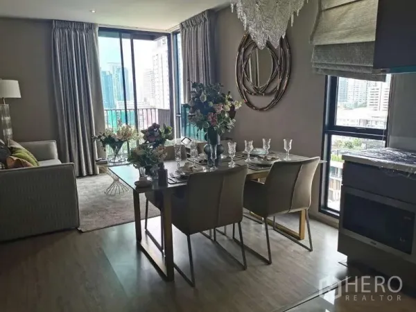 Condominium for rent or sale in Watthana, Bangkok - Dining area set for four beside balcony and living room with city views.