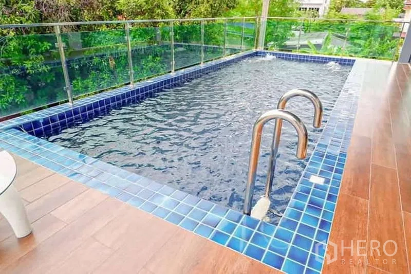 独立式住宅 出售在Lat Phrao, Bangkok - 蓝色瓷砖私家泳池近景，配不锈钢梯与玻璃护栏。