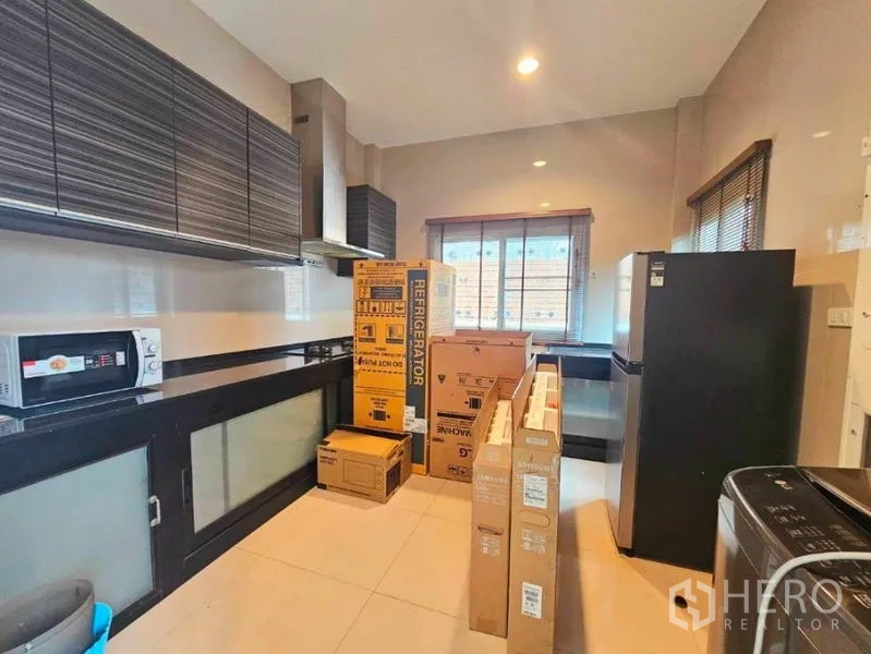 Detached House for rent in Chatuchak, Bangkok - Fitted kitchen with cabinets, range hood and large window, with new appliances in boxes.