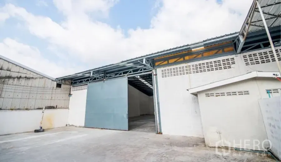 货栈 出租在Mueang Samut Prakan, Samut Prakan - 宽阔装卸场地，蓝色滑动大门，带顶通道直达仓库内部。