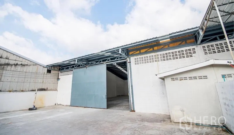 货栈 出租在Mueang Samut Prakan, Samut Prakan - 宽阔装卸场地，蓝色滑动大门，带顶通道直达仓库内部。