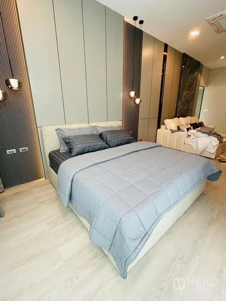 Detached House for rent - Bedroom with grey bedding, accent wall panels and an adjacent sitting area.