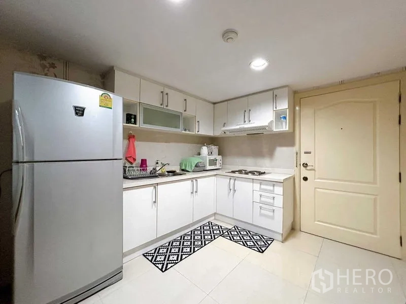 公寓 出租在Watthana, Bangkok - 实用L型厨房，白色橱柜、炉灶、微波炉和大冰箱。