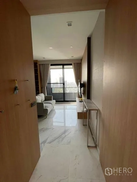 Condominium for rent or sale in Bang Rak, Bangkok - Entry hallway leading to the living room and balcony with skyline beyond.