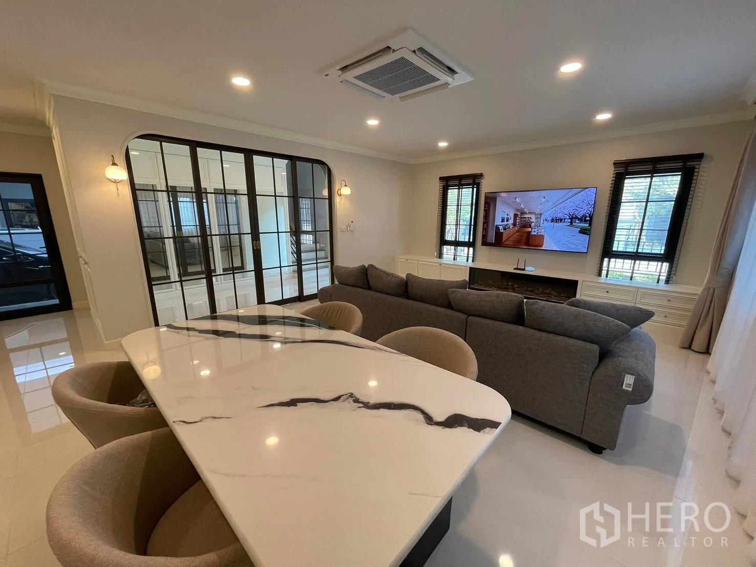 Detached House for rent in Bang Phli, Samut Prakan - Open-plan dining and living space with marble dining table, plush chairs, ceiling cassette air-con, and sectional sofa.