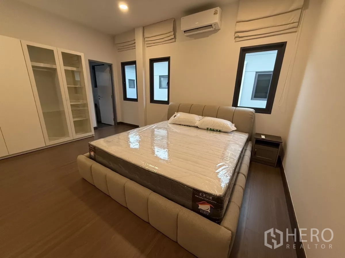 独立式住宅 出租在Bang Phli, Samut Prakan - 明亮卧室，软包床、衣柜与木地板。