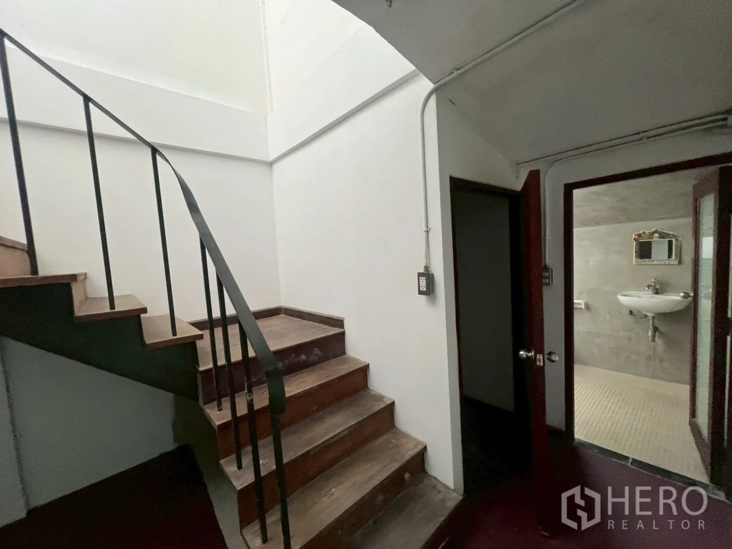 Home Office for rent in Watthana, Bangkok - Stair landing with doors to a restroom and utility area, plus a wall-mounted sink.