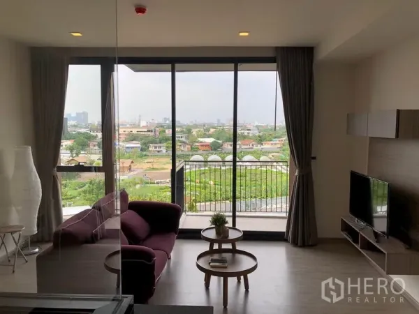 Condominium for rent in Watthana, Bangkok - Bright living room with floor‑to‑ceiling windows, balcony, and open green city views at Mori Haus condominium.