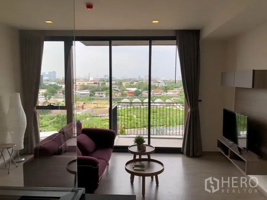 Condominium for rent in Watthana, Bangkok - Bright living room with floor‑to‑ceiling windows, balcony, and open green city views at Mori Haus condominium.