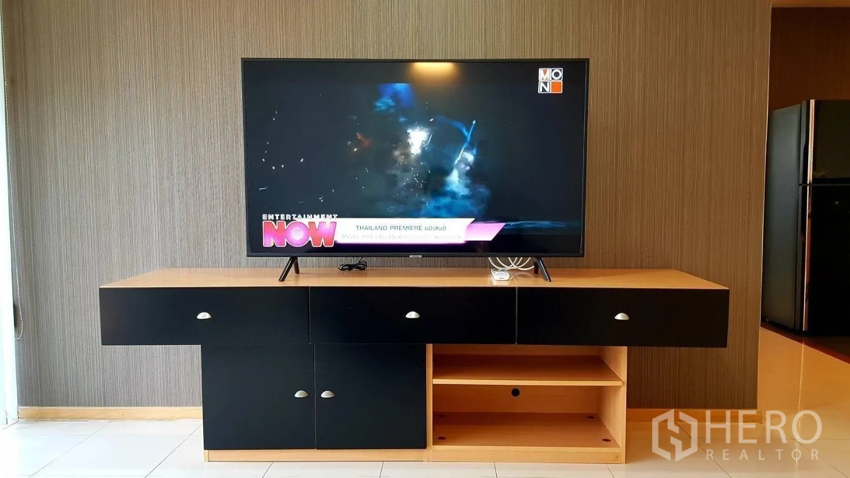 公寓 for rent in Khlong Toei, Bangkok - 客厅内，平板电视置于木质电视柜上，背景为纹理墙面。
