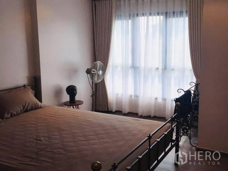公寓 出售在Watthana, Bangkok - 温馨卧室，金属床架、透光窗帘与立式风扇，自然采光充足。