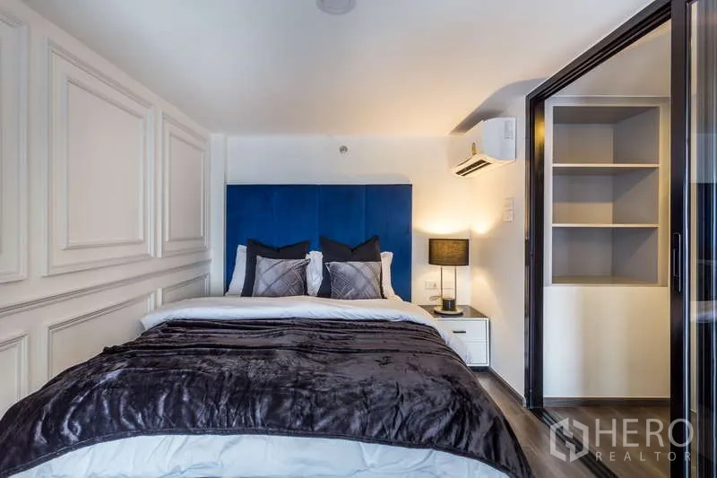 Condominium for rent - Cozy loft bedroom with blue headboard, sliding glass door, and built-in shelving.