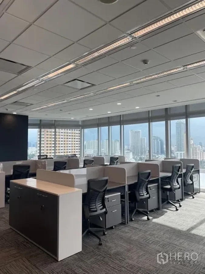 Office Space for rent in Dusit, Bangkok - Bright workstation rows beside expansive glazing with a Bangkok skyline backdrop.