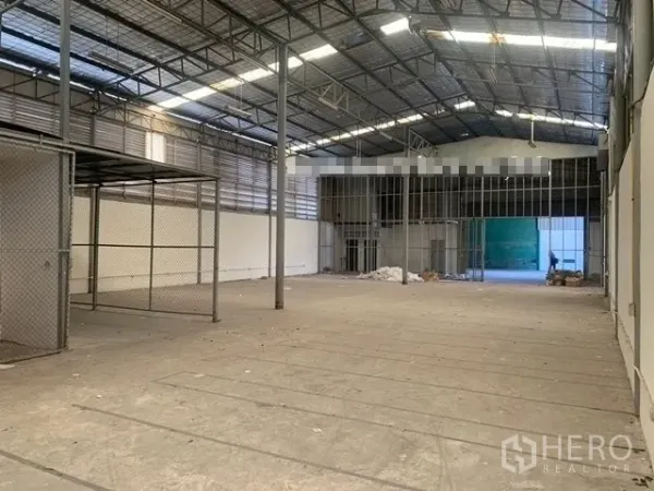 Warehouse for rent in Suan Luang, Bangkok - Spacious warehouse hall with a high steel truss roof, mesh storage area, and wide loading entrance.