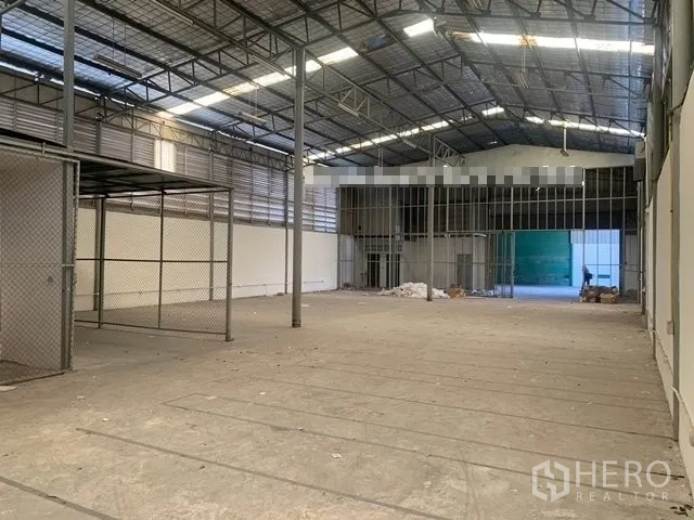 Warehouse for rent in Suan Luang, Bangkok - Spacious warehouse hall with a high steel truss roof, mesh storage area, and wide loading entrance.