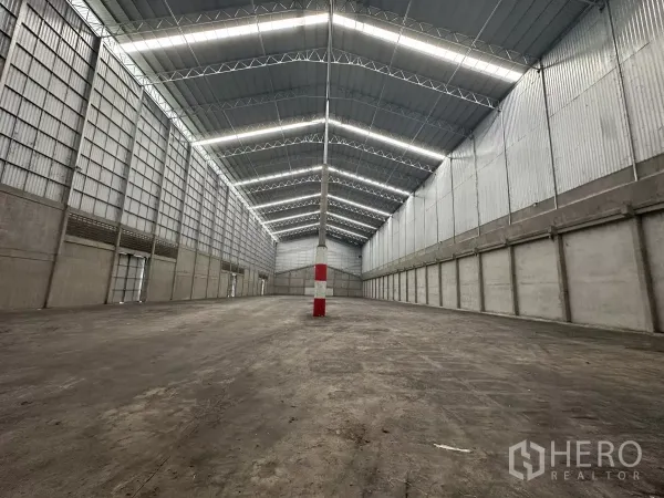 Warehouse for rent in Mueang Pathum Thani, Pathum Thani - Clear‑span warehouse floor with reinforced concrete surface and evenly lit high roof.
