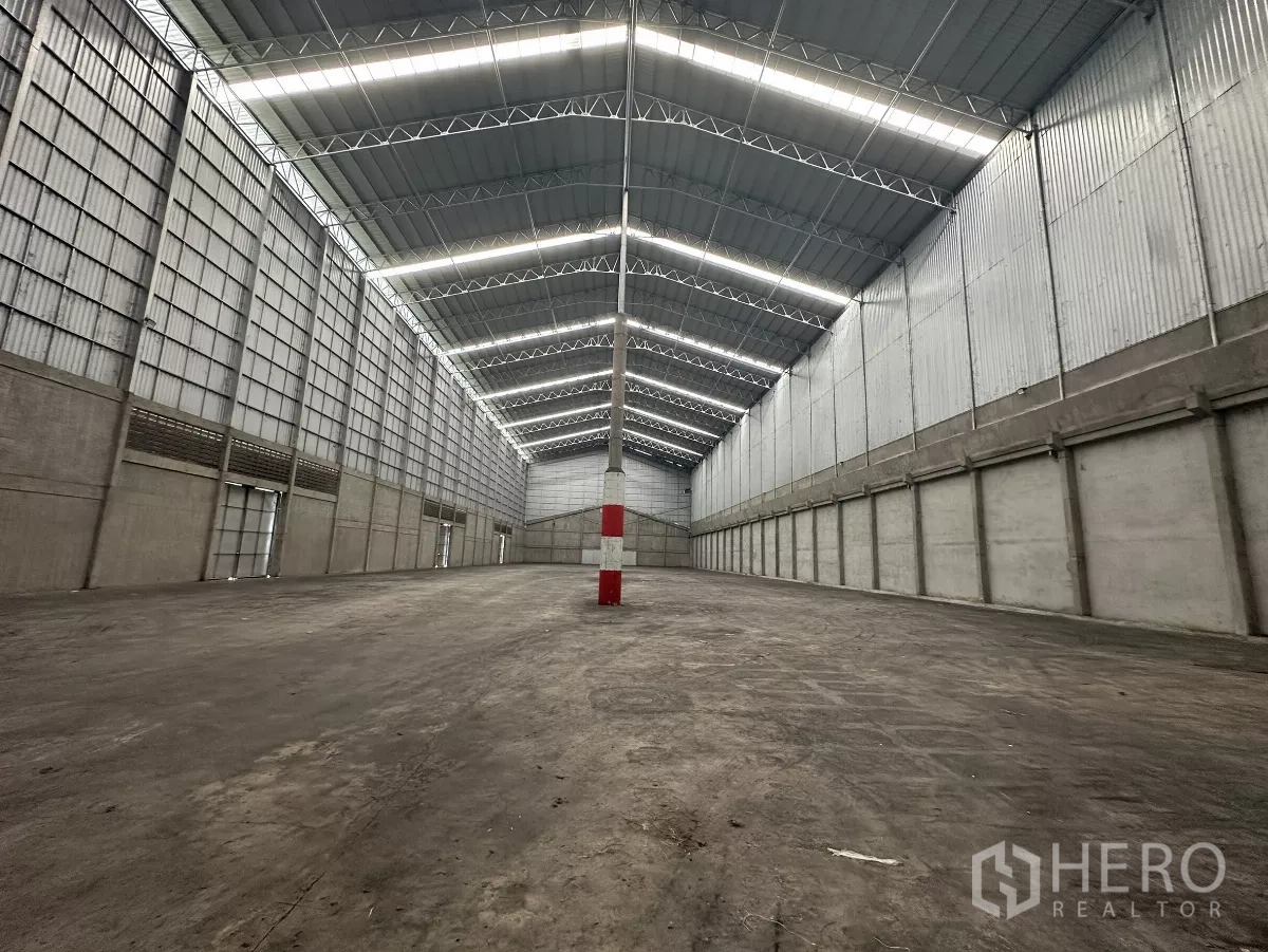 Warehouse for rent in Mueang Pathum Thani, Pathum Thani - Clear‑span warehouse floor with reinforced concrete surface and evenly lit high roof.