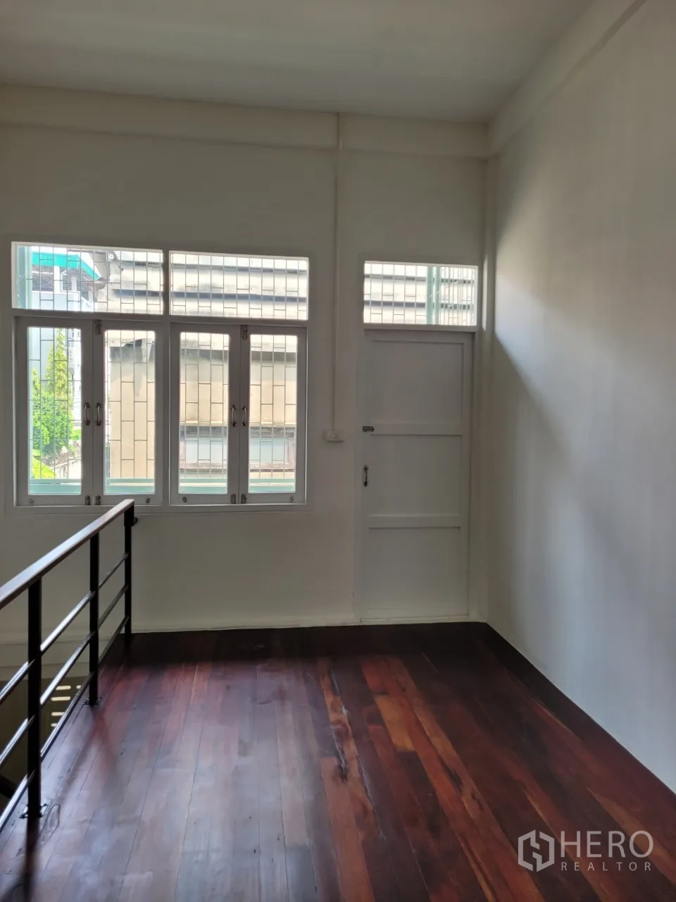 Shophouse for rent in Khlong Toei, Bangkok - Upper mezzanine-style area with railing and windows overlooking the street.