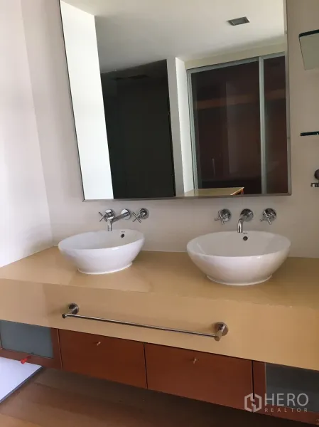 Condominium for rent in Khlong Toei, Bangkok - Bathroom vanity with two round vessel sinks beneath a large mirror.