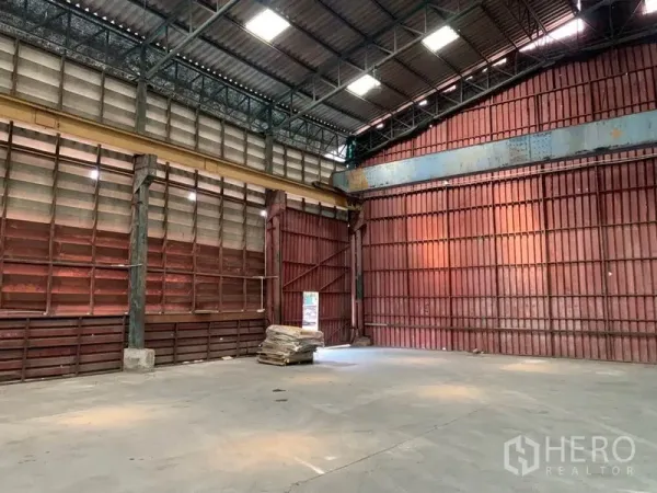 Warehouse for rent in Bang Kho Laem, Bangkok - Corner view showing tall red metal walls and open, column‑free storage space.