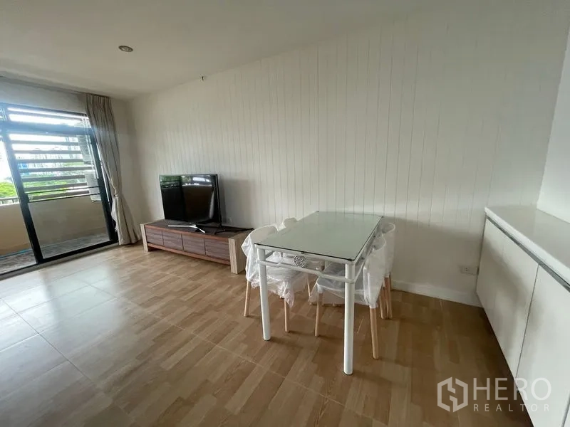 Condominium for rent in Watthana, Bangkok - Dining corner with a glass table beside the TV and access to the balcony.